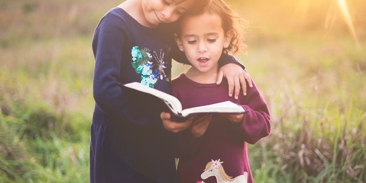 Two children reading the book together in warm evening light